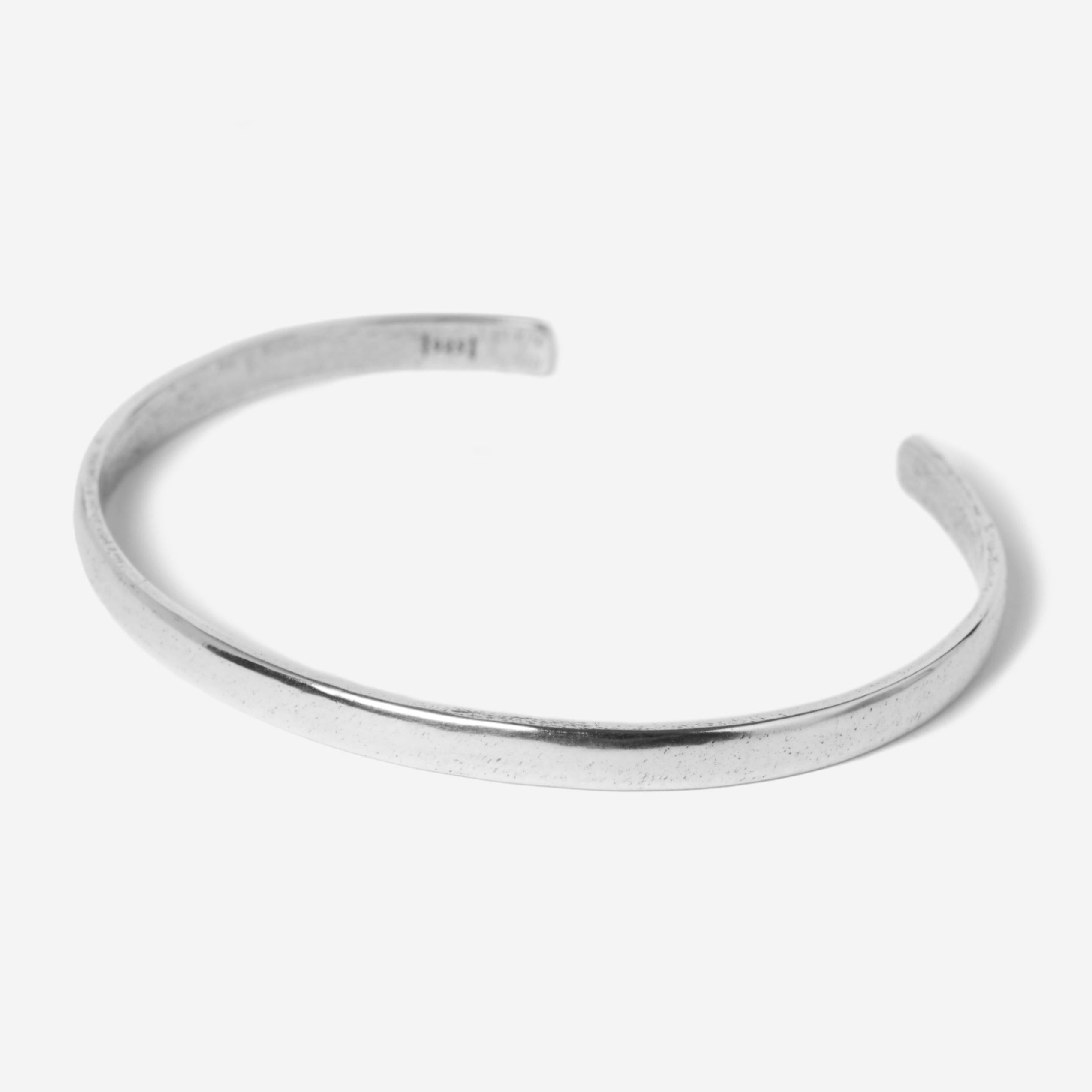 A simple, thin, silver open cuff bracelet with a smooth, slightly reflective surface, displayed on a plain white background.