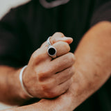 Close-up of a man wearing the Abyss Ring with black onyx stone, showing a strong grip pose