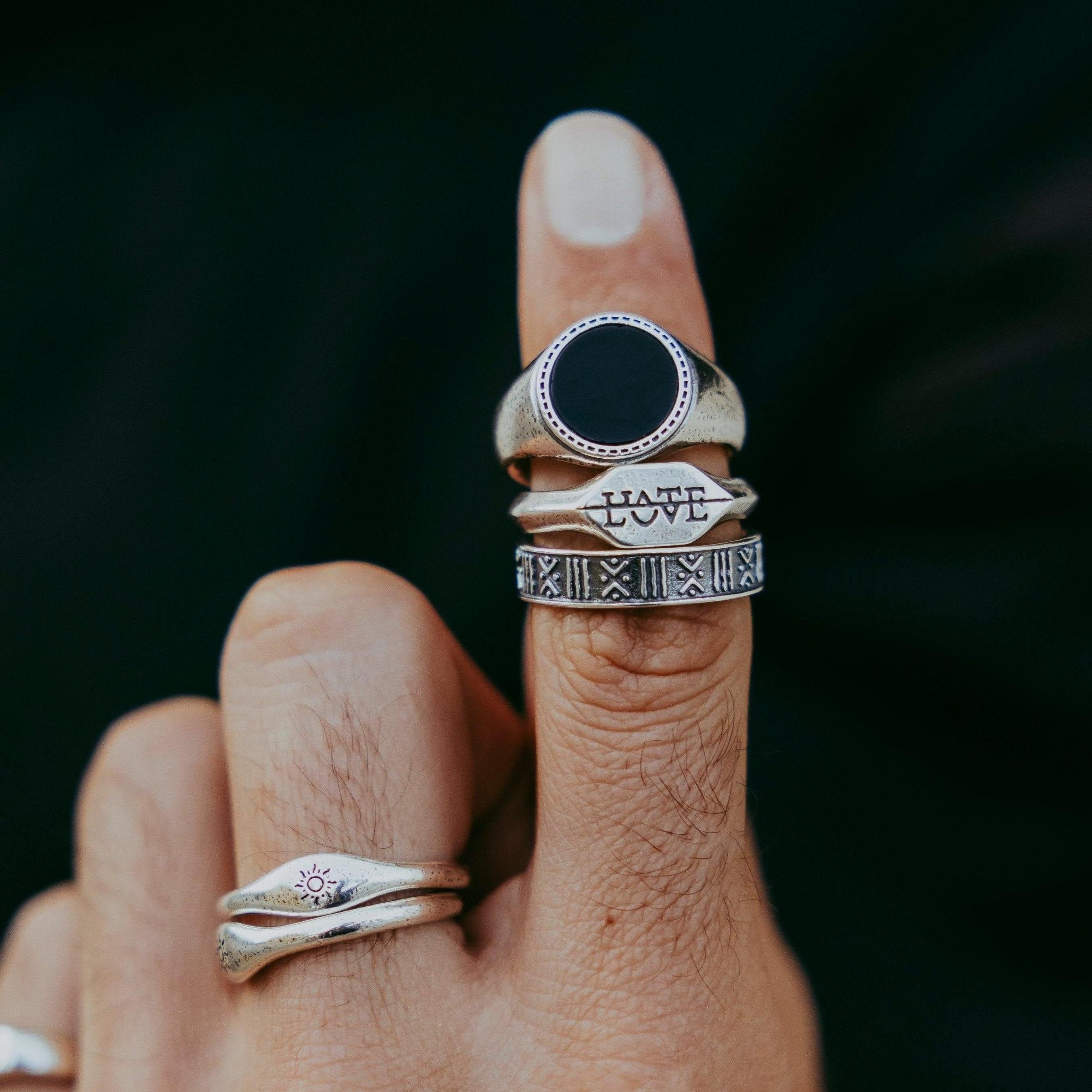 Three rings on an index finger, featuring a polished round onyx ring 