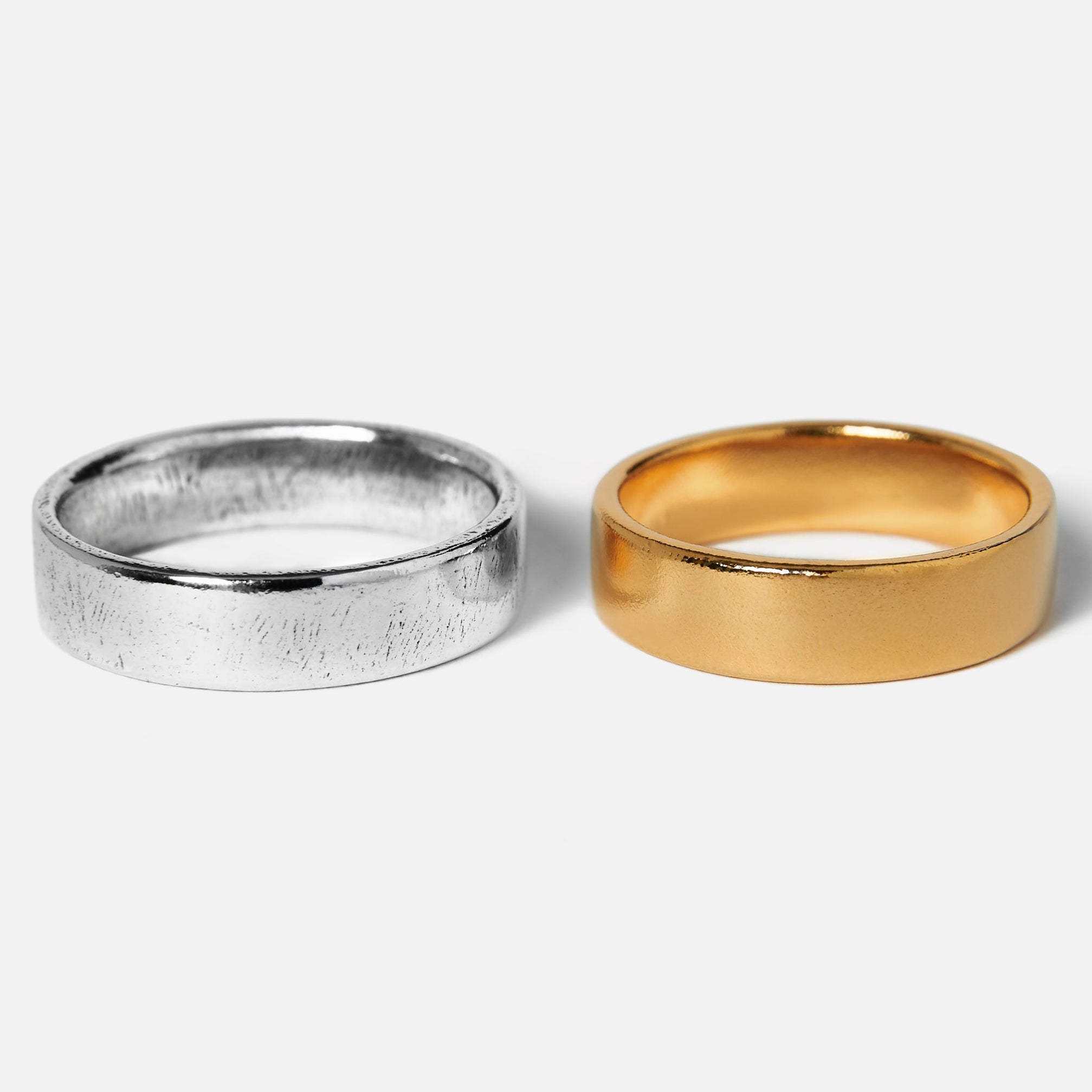 Two rings, one silver and one gold, on a white background