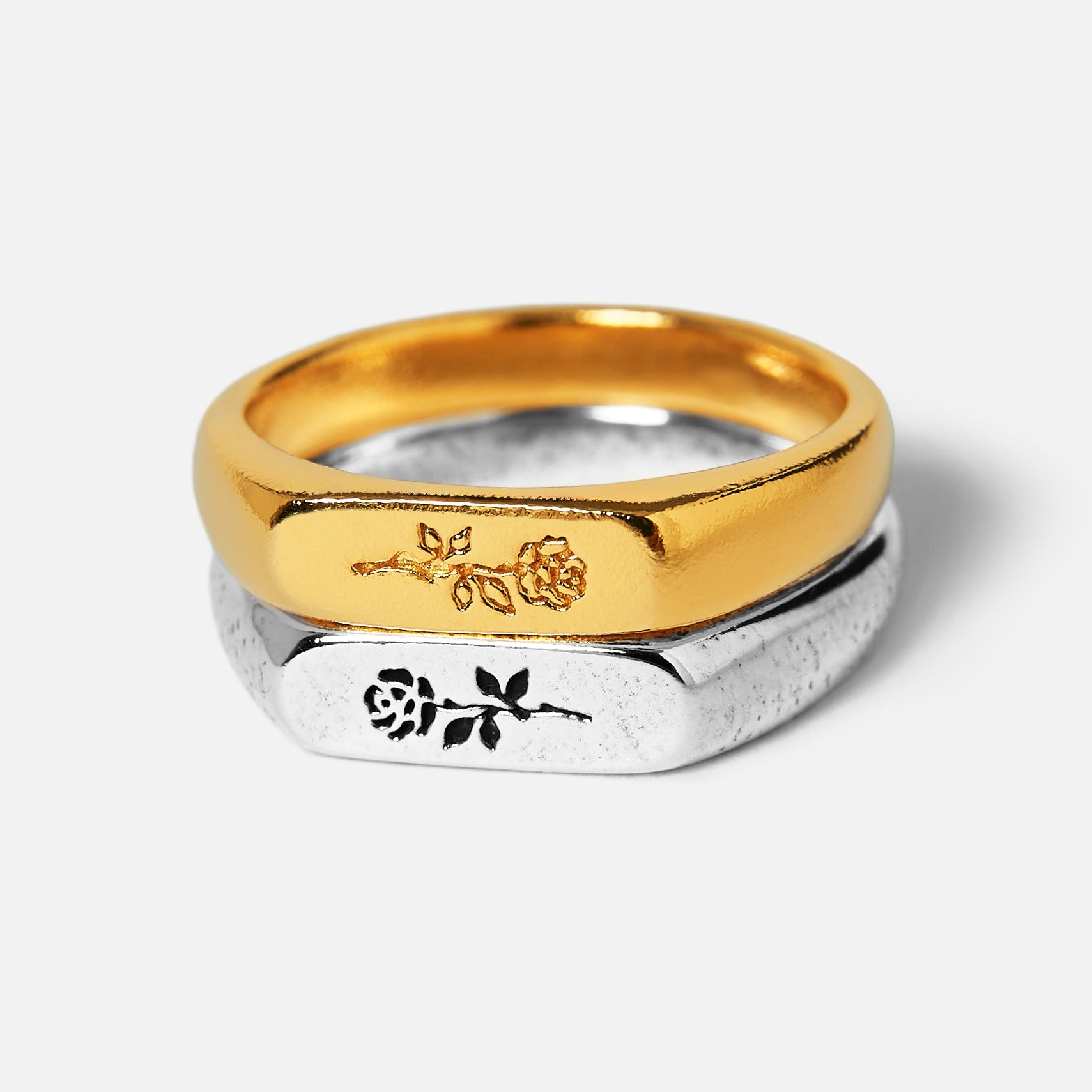 Two gold and silver rings with engraved designs on a white background